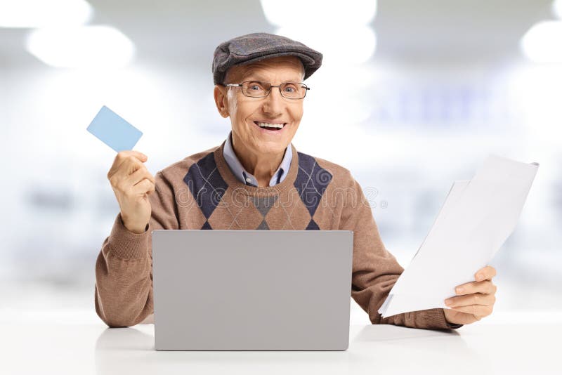 Χαμογελώντας ανώτερο άτομο που πληρώνει τους λογαριασμούς με μια πιστωτική κάρτα on-line σε έναν φορητό προσωπικό υπολογιστή